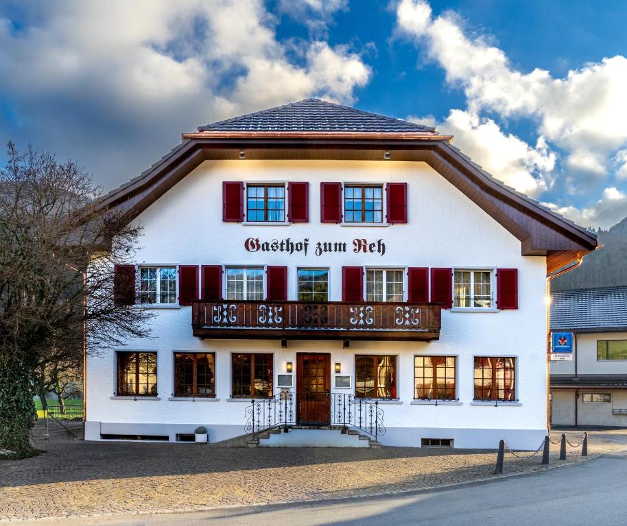 a large white building with red shutters at Gasthof zum Reh - Self Check-in 