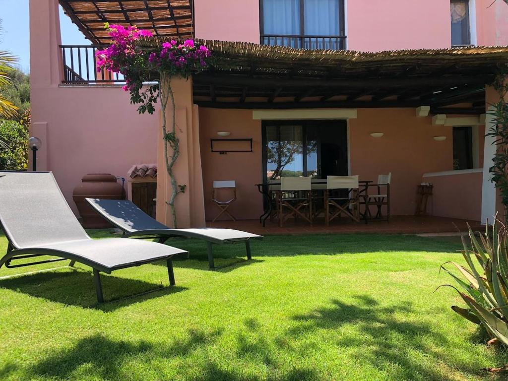 a yard with two chairs and a table and a house at Appartamento Stintino in Cuile Pazzoni