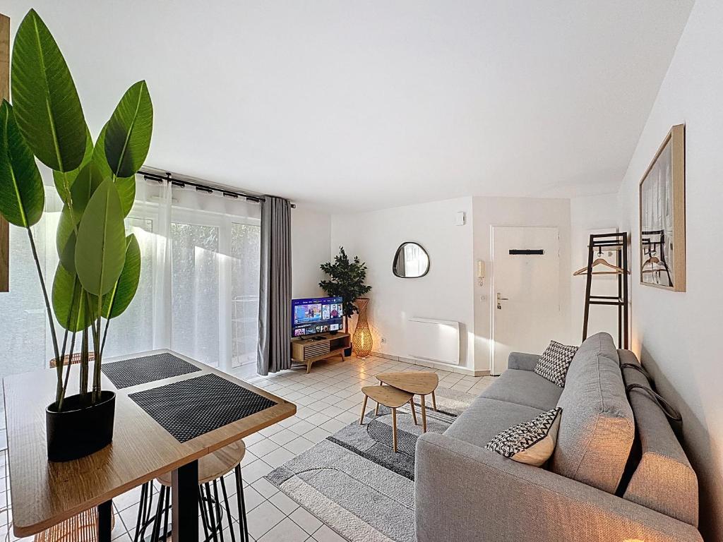 een woonkamer met een bank en een tafel bij Studio Moderne avec jardin et garage in Nanterre