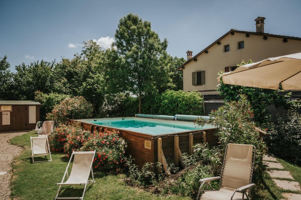 a swimming pool in a yard with chairs and an umbrella at Agriturismo Ca' di Mazza in Monzuno