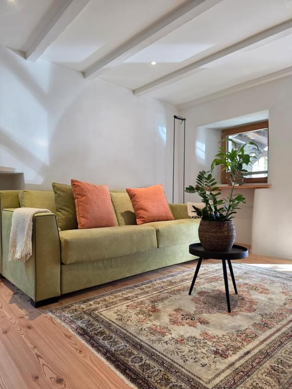 a living room with a green couch and a table at Cavigliano Rustico - free parking in Cavigliano
