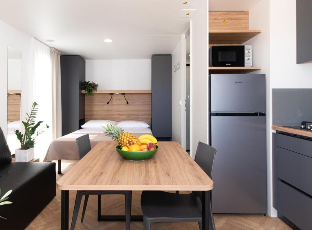 a kitchen and a table with a bowl of fruit on it at Camping Resort Šibenik in Jadrija