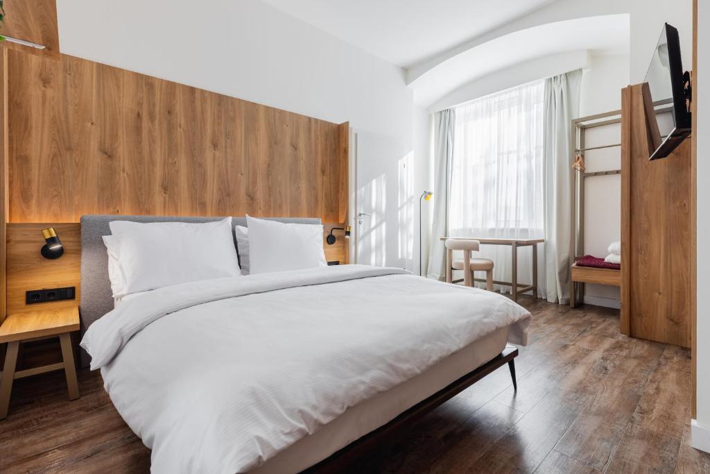 une chambre avec un grand lit blanc avec une tête de lit en bois dans l'établissement FortyPlusOne Apartments Vienna, à Vienne