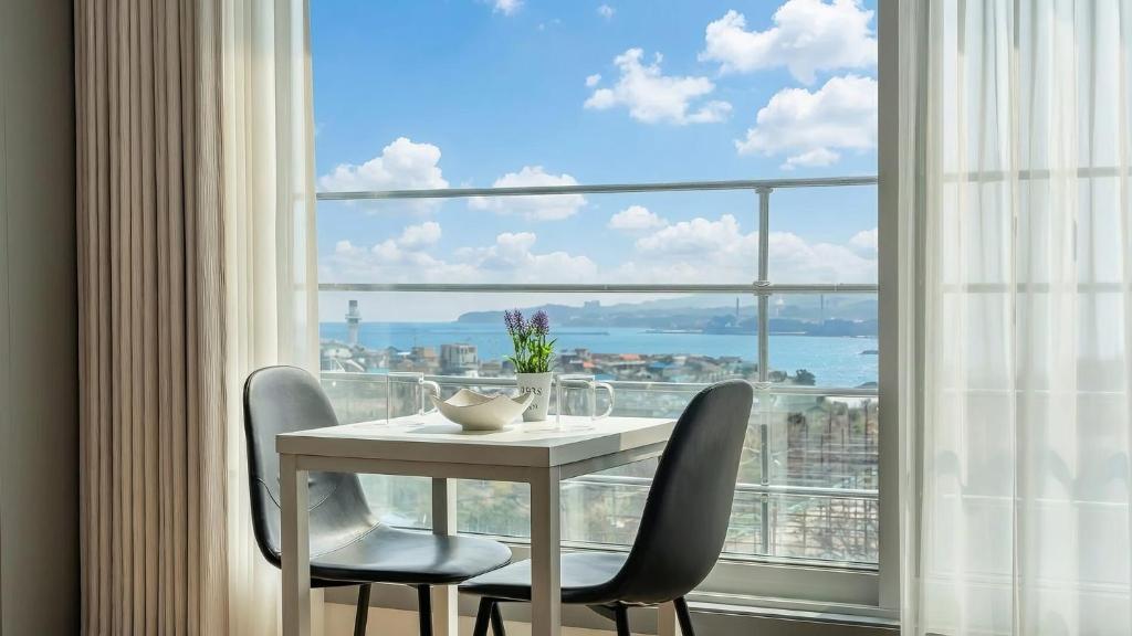 a table and chairs in a room with a large window at Donghae Hill Stay Pension in Donghae