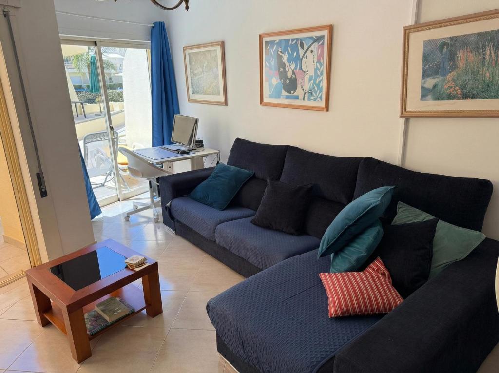 ein Wohnzimmer mit einem Sofa und einem Tisch mit einem Laptop in der Unterkunft Stylish 2BR Vilamoura Escape with Pool & Golf Nearby -15 Percent Off in Quarteira