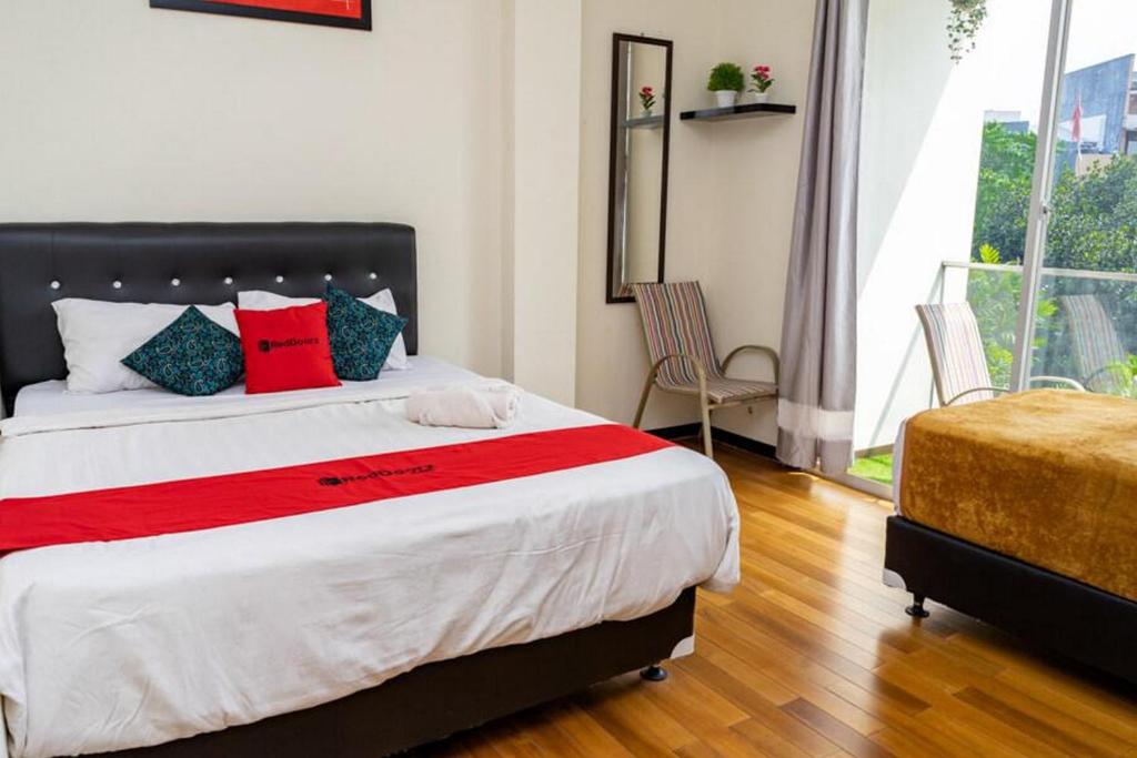 1 dormitorio con 1 cama grande con almohadas rojas y azules en RedDoorz near Setrasari Mall 4, en Bandung