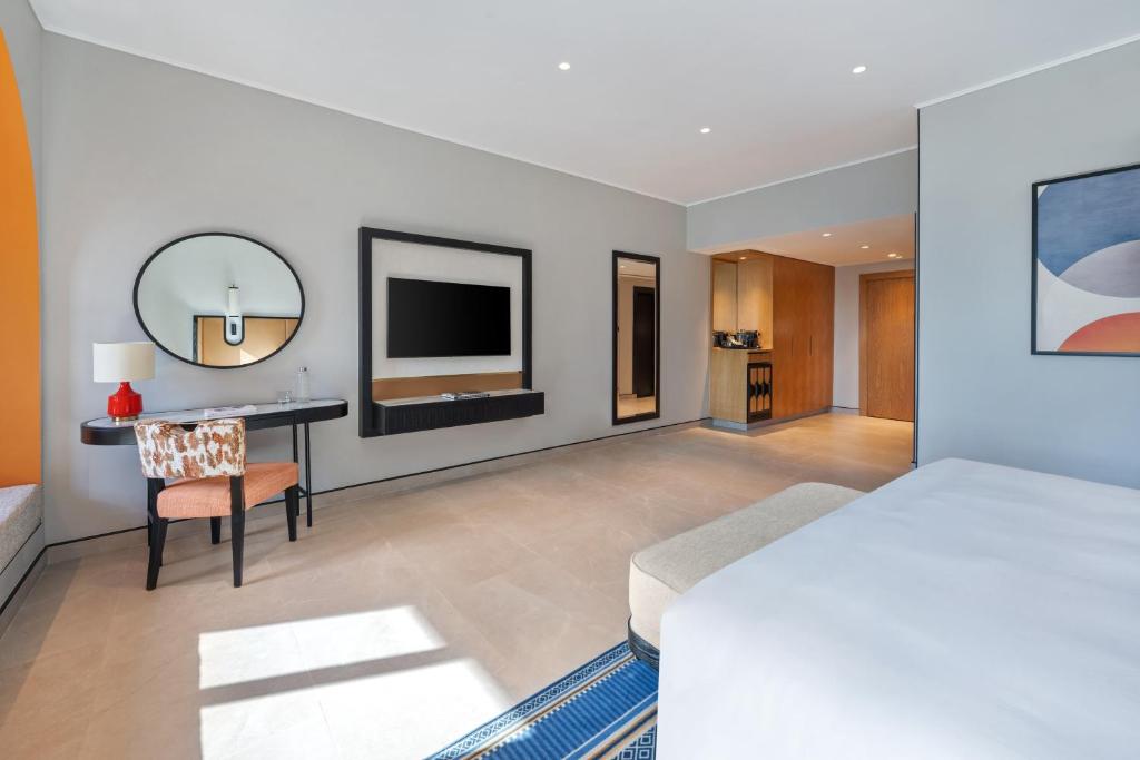 a bedroom with a bed and a desk and a television at Oaks Ibn Battuta Gate Dubai in Dubai