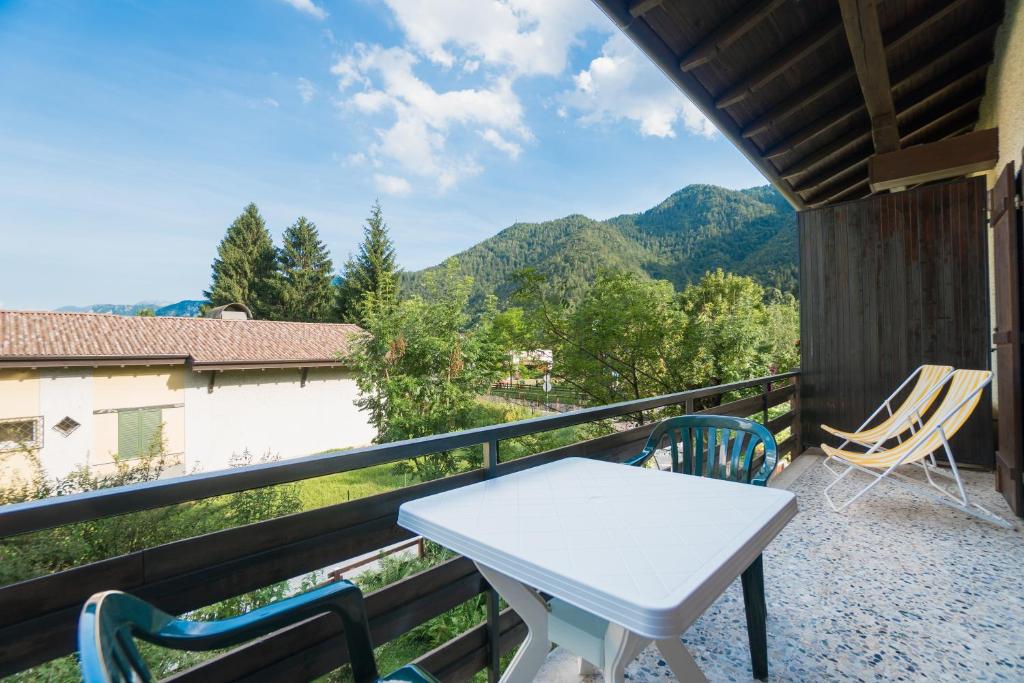 una mesa blanca y sillas en un balcón con montañas en Casa Luisella, en Pieve di Ledro