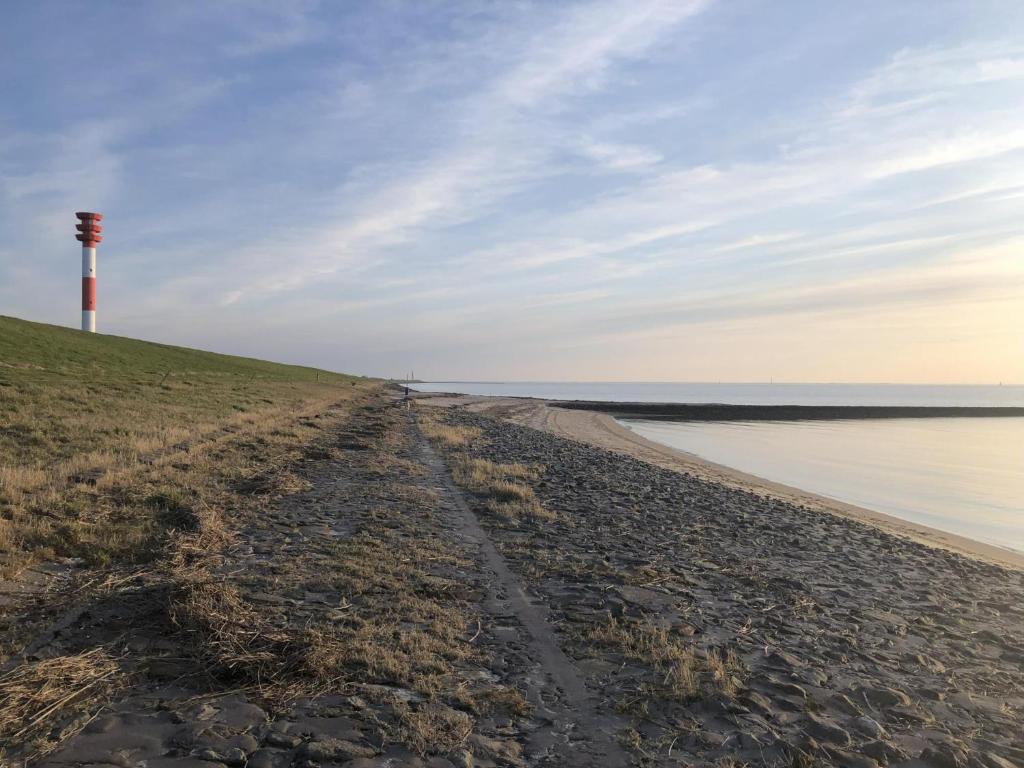 a dirt road leading to a lighthouse on a beach at NordseeResort Tossens - Seaside Corner in Tossenserdeich