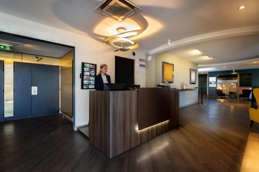 エクス・アン・プロヴァンスにあるBest Western Hotel le Galice Aix-en-Provenceの事務ロビーの窓口に立つ女