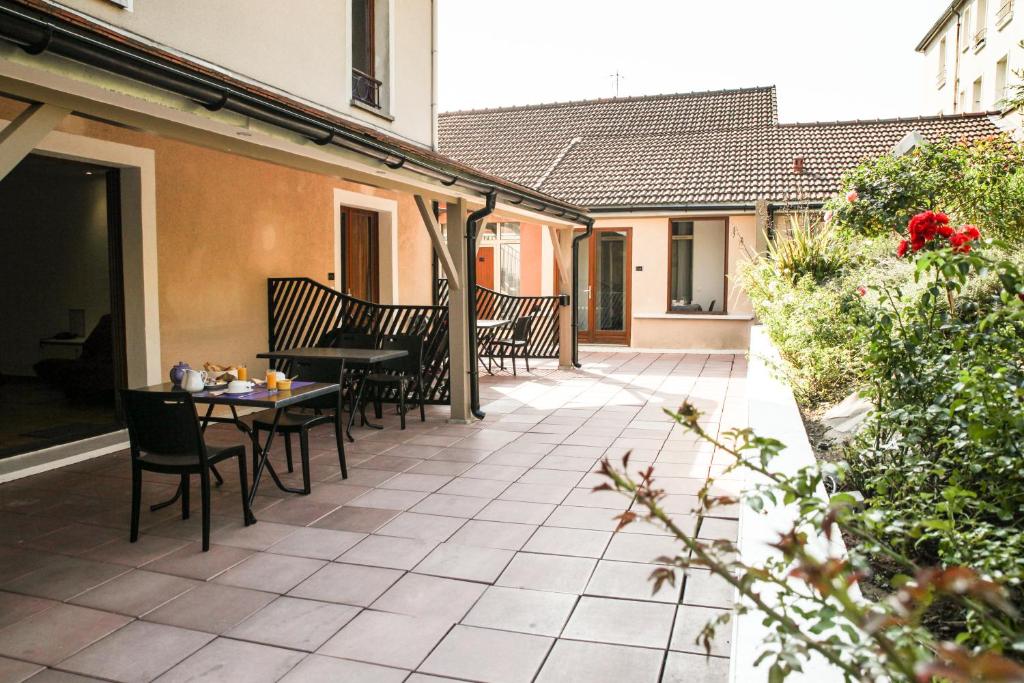 a patio with chairs and a table on a building at La Ferme Des Barmonts in Villejuif