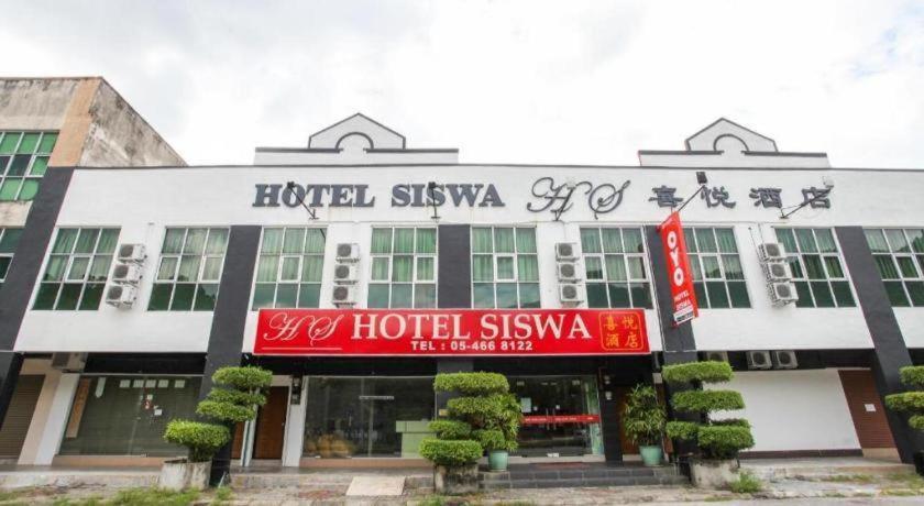 Un hotel con un cartel rojo delante de un edificio. en OYO 89539 Hotel Siswa, en Kampar