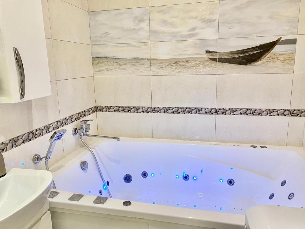 a bathroom with a bath tub with a boat on the wall at Jacuzzi With light Nauki Avene in Kharkiv