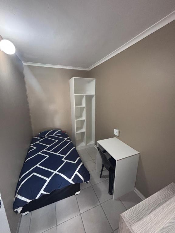 a small bedroom with a bed and a desk at The Easy Stay in Durban