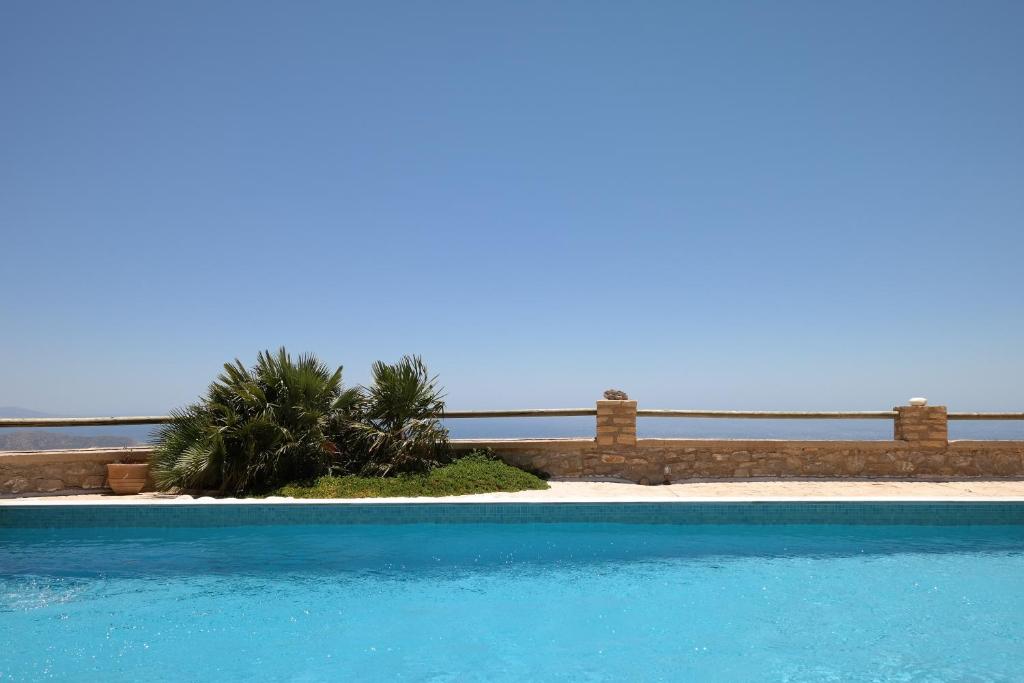 a blue swimming pool with a palm tree in the background at Keramos Villa in Kerames