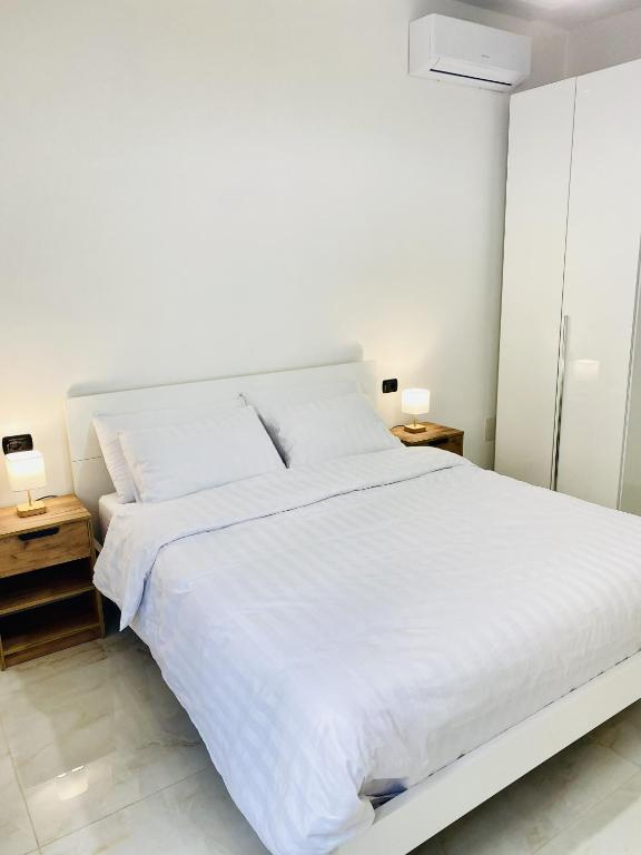 une chambre blanche avec un lit blanc et deux tables de nuit dans l'établissement Corso 42, à Novara