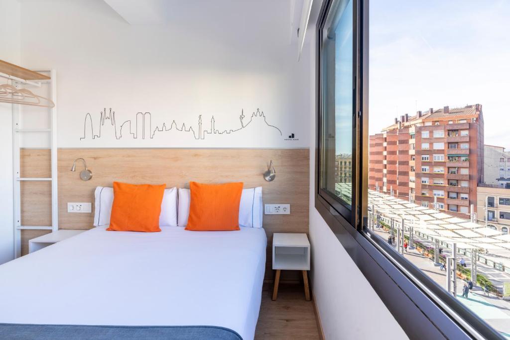 una camera da letto con un letto con cuscini arancioni e una finestra di Hostal Sans a Barcellona