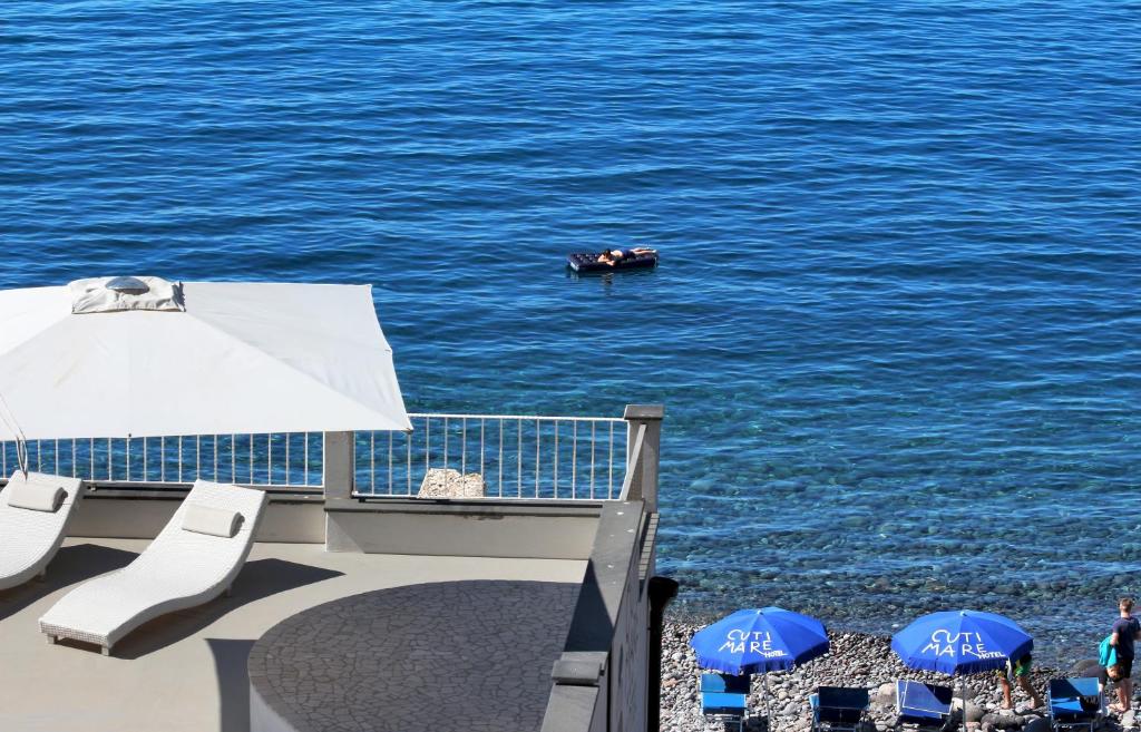 um barco na água com cadeiras e um guarda-sol em Hotel Cutimare - Aeolian Charme em Acquacalda