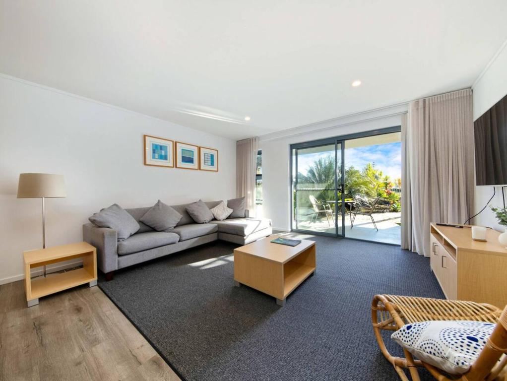 a living room with a couch and a table at Corrigans Poolside Apartment Batehaven in Batehaven
