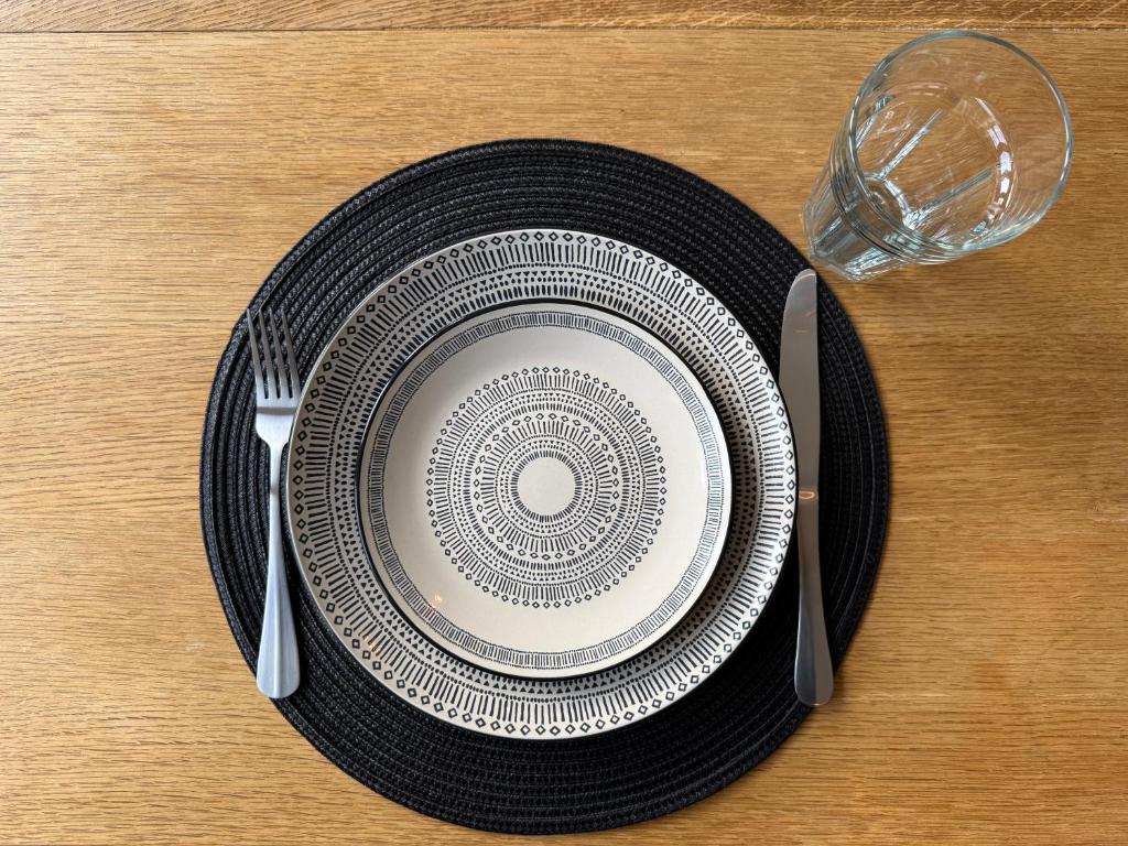 un piatto su un tavolo con un bicchiere e una forchetta e un coltello di Modern 3-Bedroom Home in Bletchley, Milton Keynes a Bletchley