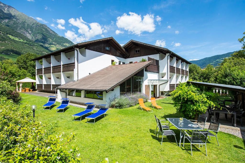a building with chairs and a table in the yard at Pension Astoria in Naturno