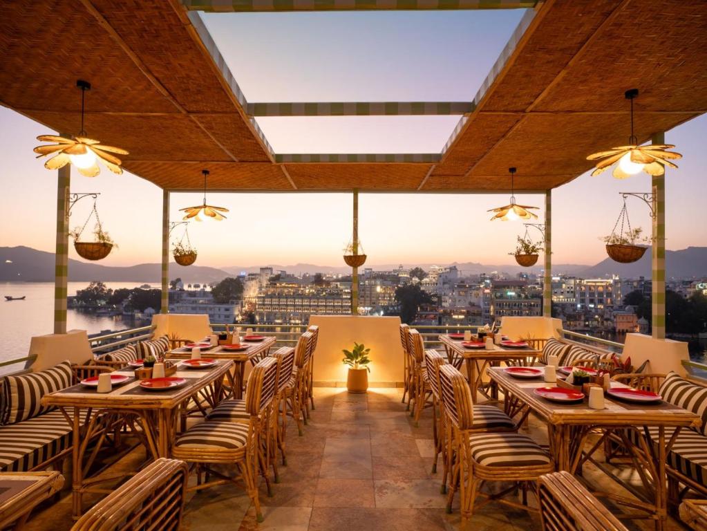un restaurant avec des tables et des chaises et une vue sur la ville dans l'établissement Bun and Bunks, à Udaipur