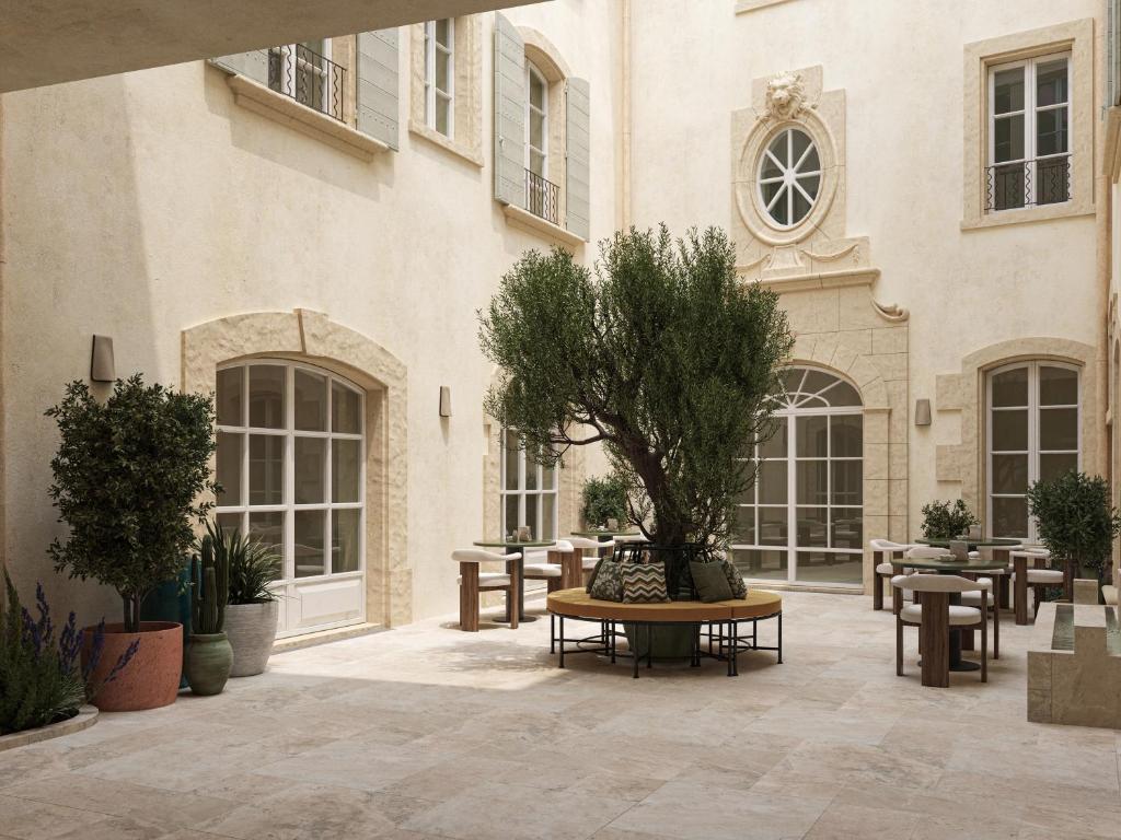 un cortile con tavoli e un albero in un edificio di Hôtel de La Fontaine a Lourmarin