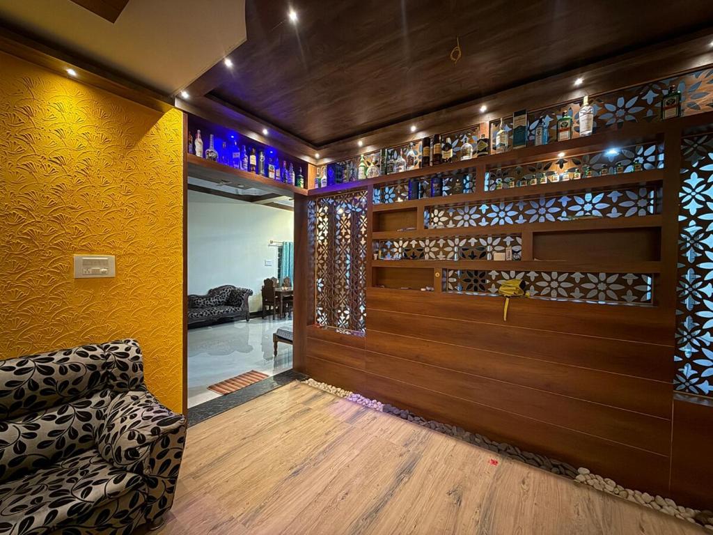 een woonkamer met een bank en een muur vol wijnglazen bij Palmstone Retreat in Gādigarpālya
