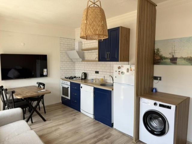 a kitchen with blue cabinets and a table with a dining room at Aden Suit Apart Otel in Fethiye