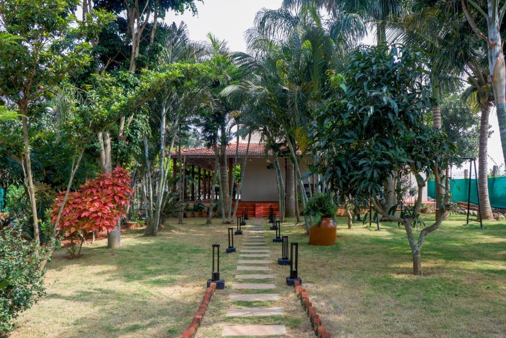 a path in a garden with trees and a building at Eco Serenity Pet-friendly Charming 2-BHK Villa With Lush Garden, Gazebo, Private Pool & Open Dining Close to Nandi Hills in Oddarahalli