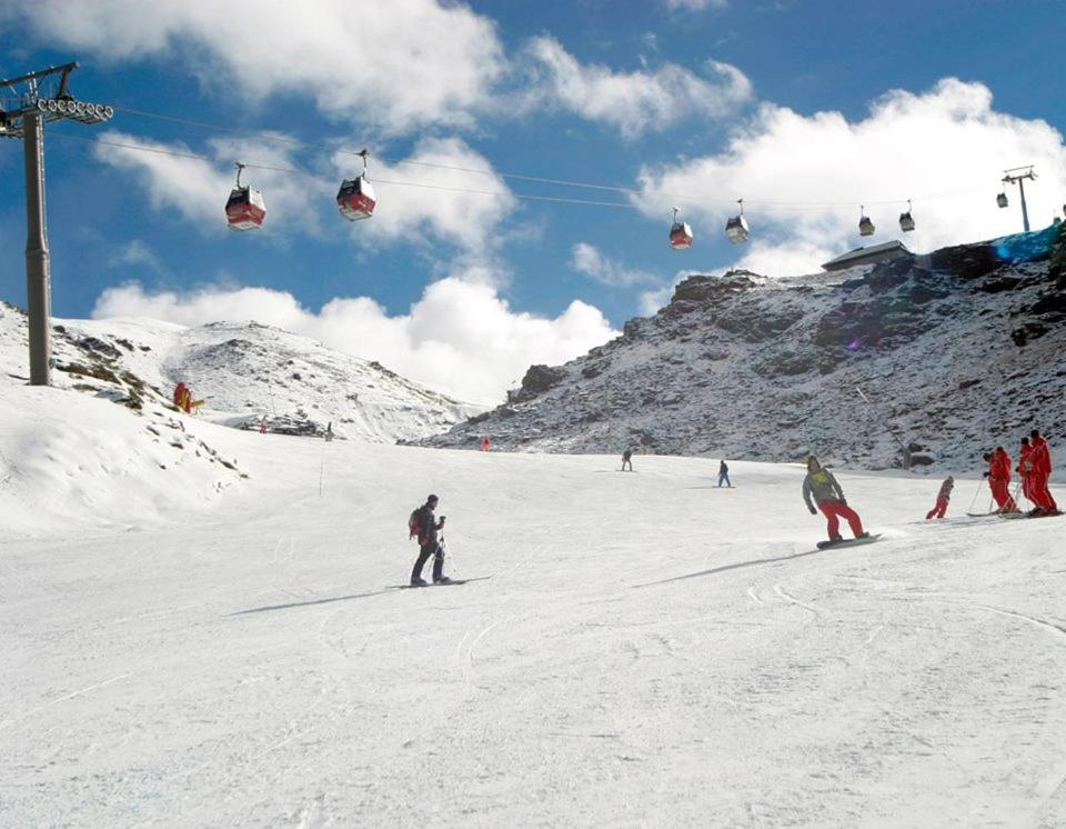 eine Gruppe von Menschen fährt mit Skiern einen schneebedeckten Berg hinunter in der Unterkunft CARMIN Alpujarras & Costa Tropical in Vélez de Benaudalla