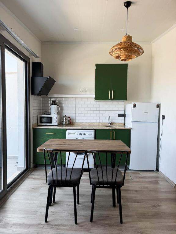 a kitchen with green cabinets and a wooden table and chairs at aden suits teras in Fethiye