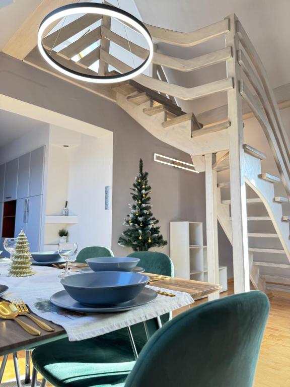 een eetkamer met een tafel met groene stoelen en een trap bij Apartament Irys in Zakopane