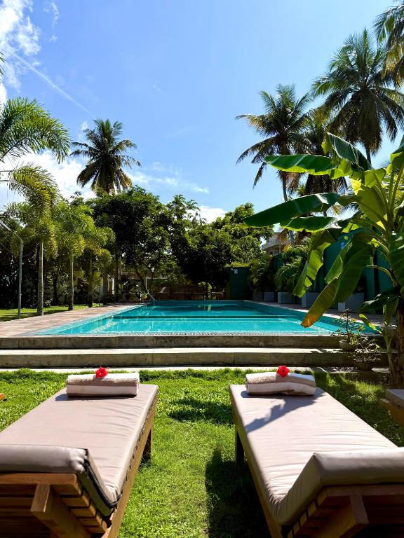 two beds in the grass near a swimming pool at Dharma Place in Ahangama