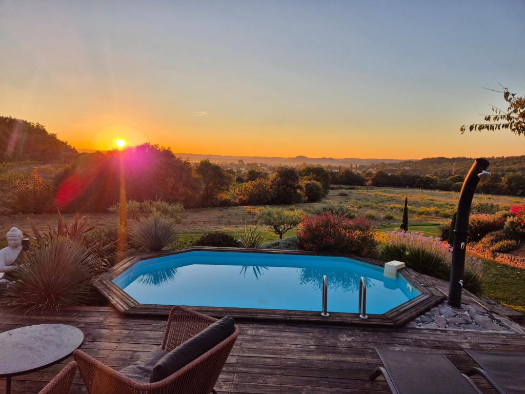 a swimming pool with a sunset in the background at La tête sous les étoiles in Lézignan-la-Cèbe