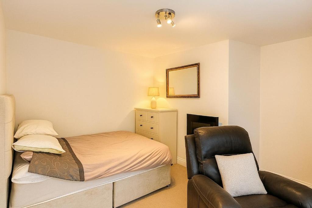 een kleine slaapkamer met een bed en een stoel bij Modern Tiny Home - Ideal for Work Stays & Parking in Pocklington