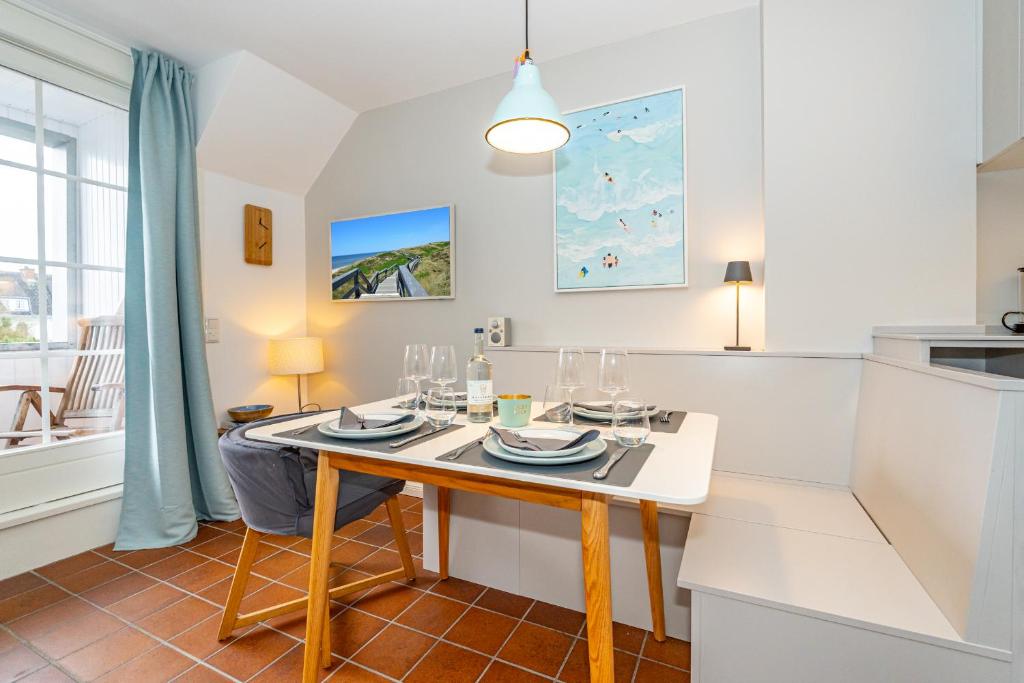 ein Esszimmer mit einem Tisch und einer Küche in der Unterkunft Syltweh in Munkmarsch