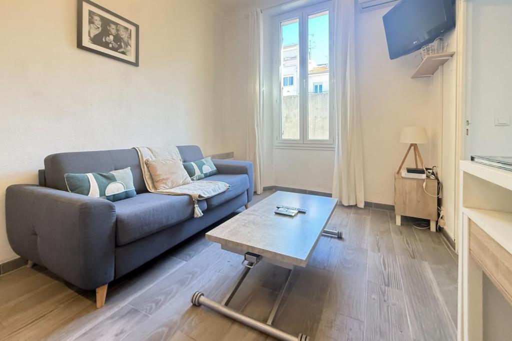 1-bedroom appartement in the center of Cannes في كان: غرفة معيشة مع أريكة زرقاء وطاولة قهوة