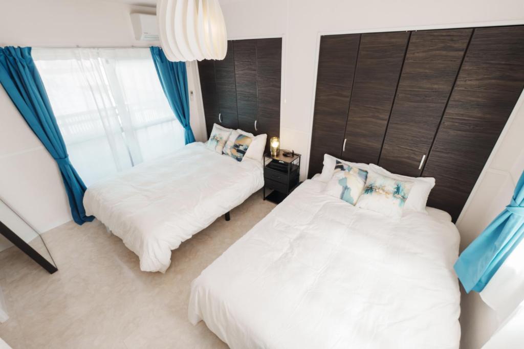 Duas camas num quarto com cortinas azuis em Sunstone Residence 2F - Free Rental Car included! em Ginowan