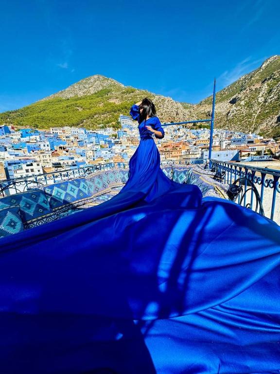 a woman in a blue dress looking at a city at Dar Nakhla in Chefchaouen