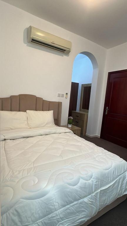 Un dormitorio con una gran cama blanca con ventana. en SM Room A1, en Abu Dabi