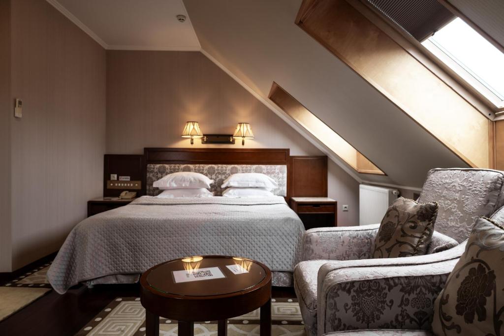een hotelkamer met een bed en twee stoelen bij AllureInn Hotel and Spa in Tsjernivsi