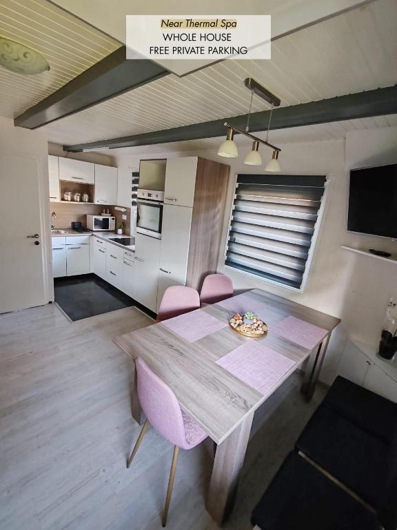 a kitchen with a wooden table and pink chairs at EMIA Family House Čatež in Brežice