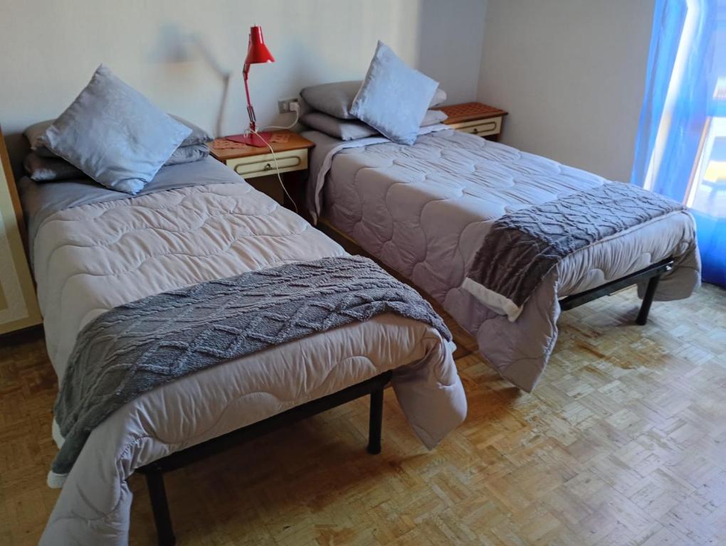 due letti uno accanto all'altro in una stanza di Casa Natale a Prato Sesia