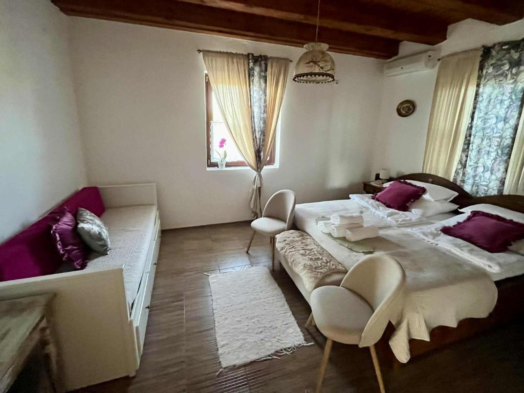 a bedroom with a large bed and two chairs at Hármaspuszta Vendégház in Fülöpszállás