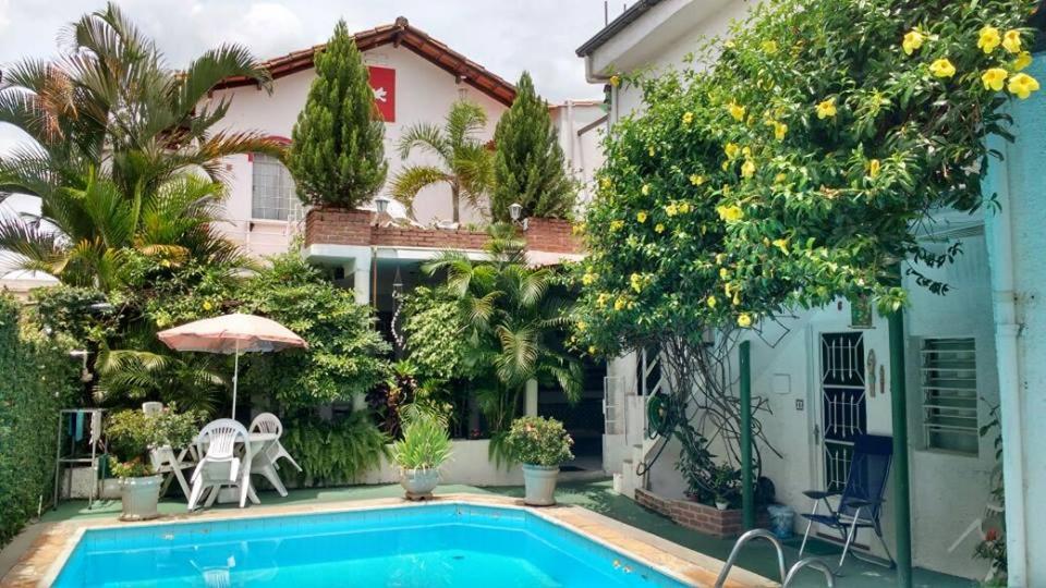 uma villa com piscina em frente a uma casa em Chale Mineiro Hostel & Pousada em Belo Horizonte