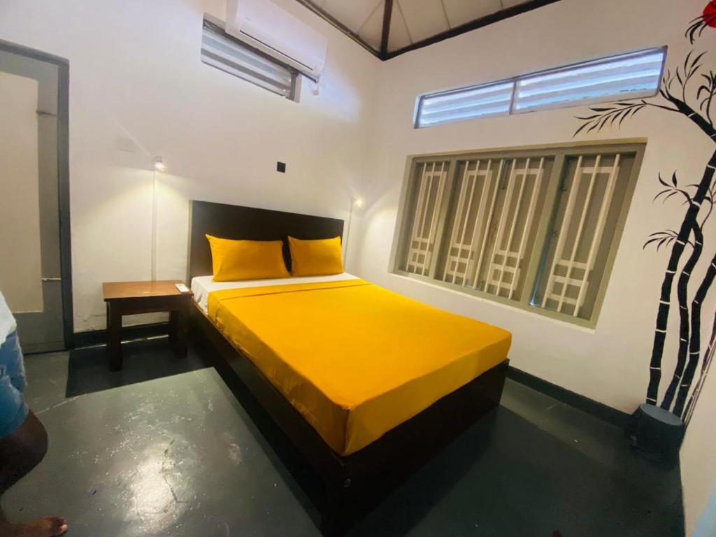 een slaapkamer met een geel bed en een raam bij Mango House in Dikwella