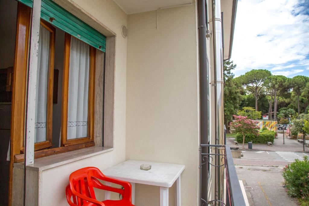 a red chair and a table on a balcony at Downtown flat 250mt from the beach in Eraclea Mare
