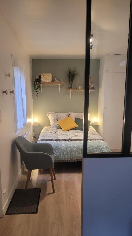 a bedroom with a bed and a chair and a mirror at Maisonnette avec jardin proche Paris in Saint-Mandé
