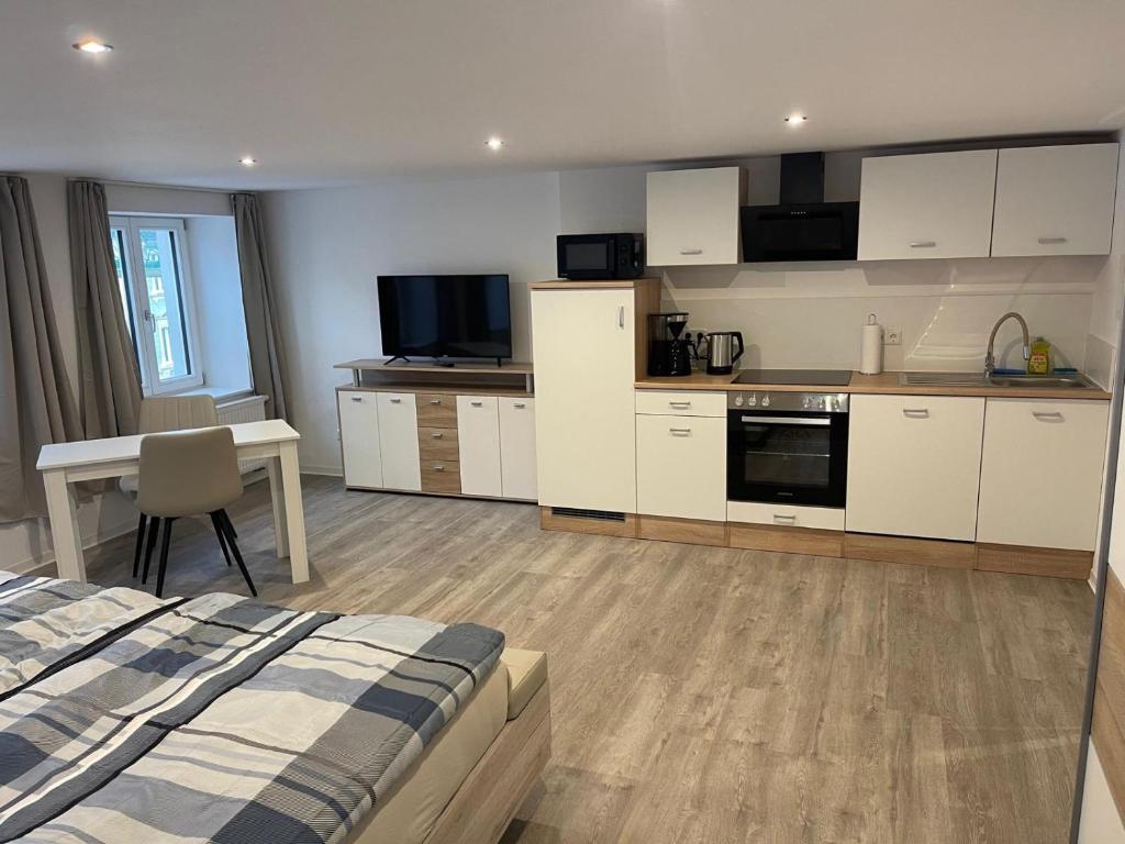 une cuisine avec des armoires blanches et un lit dans une chambre dans l'établissement Schwarzwald-Apartments-Vogel, à Hüfingen